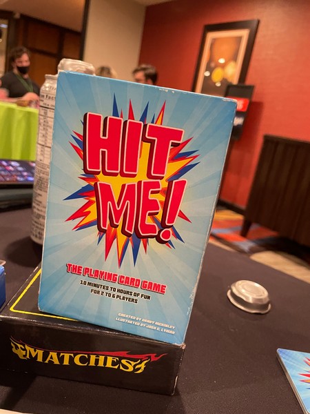 Hit Me! Box - with some people playing Wingspan in the background